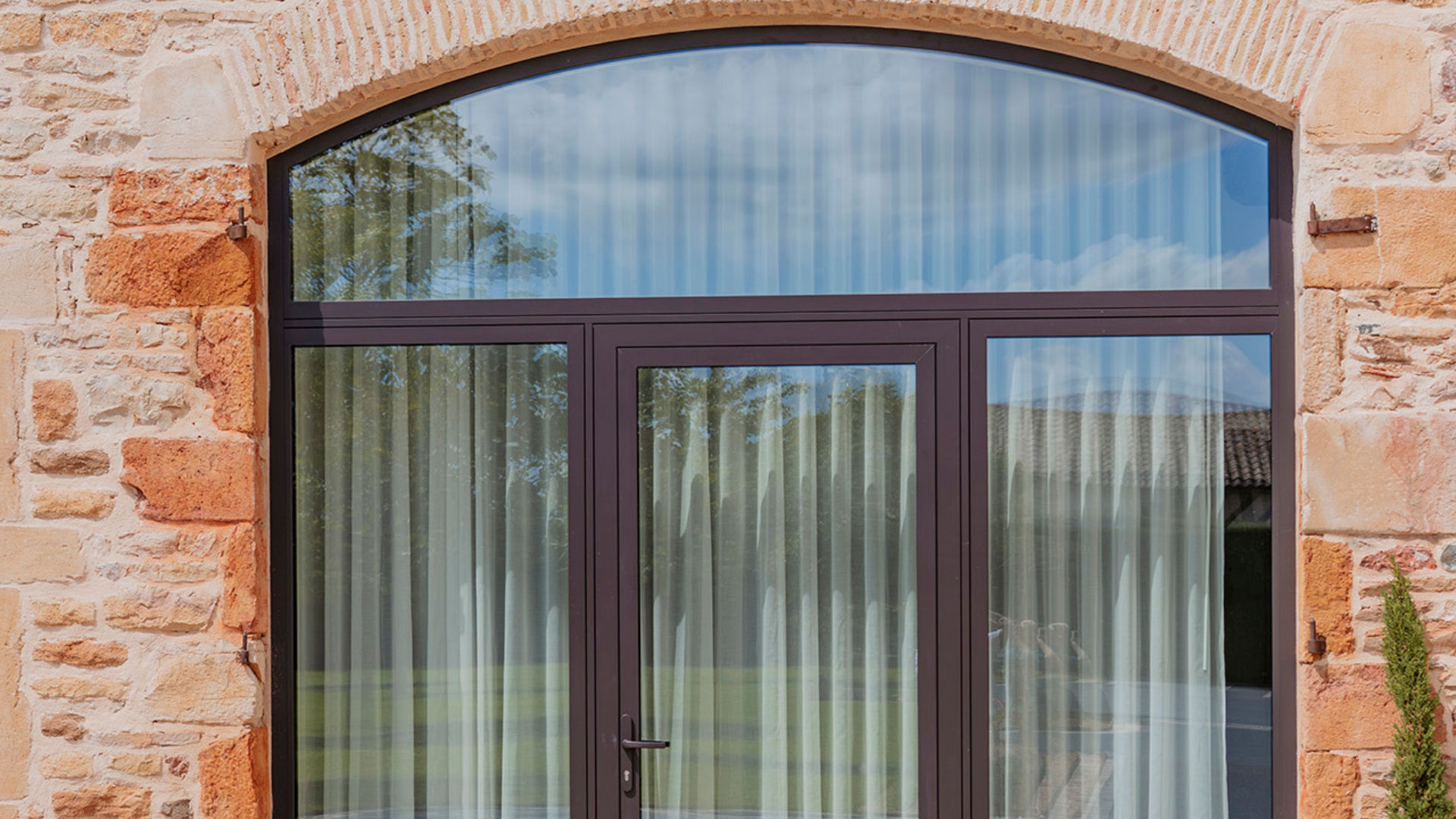 Porte fenêtre avec cintrage pour épouser parfaitement la bâtisse, par Pierret Portes&Fenêtres